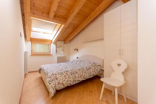 - une petite chambre avec un lit et une chaise dans l'établissement Casa Milena, à Pozza di Fassa