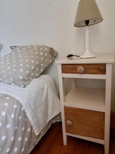 a white bed with a lamp on a night stand at Maison La Vigne - Gîtes et Chambres d'hôtes in Le Chambon-sur-Lignon
