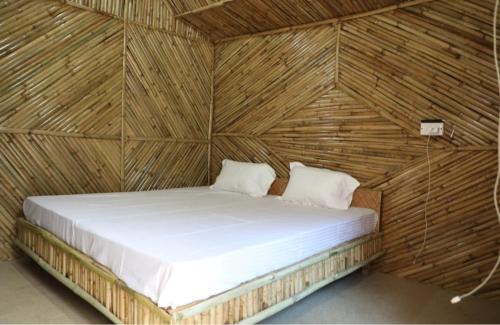 a bed in a room with a wooden wall at Hills Of Adventure, Keshudhar, Lansdowne in Lansdowne