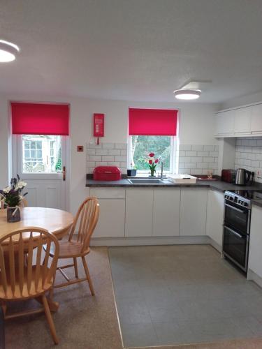 a kitchen with white cabinets and a table and chairs at Salty Smiles Cottage in Penzance