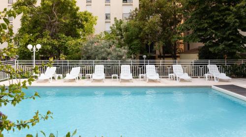 - une piscine avec des chaises blanches dans l'établissement Appart Hotel Corte HR, à Corte