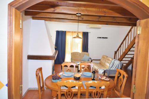 uma sala de jantar com uma mesa e cadeiras e um sofá em Casa Coriska no Algoz