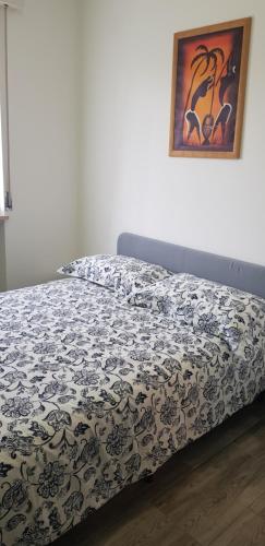 ein Bett mit einer schwarzen und weißen Bettdecke und einem Bild in der Unterkunft Appartamento San Miguel in Pasian di Prato