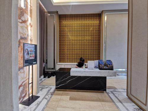 a woman sitting at a counter in a lobby at Transpark Cibubur By Arsakha Property Management in Kalimanggis