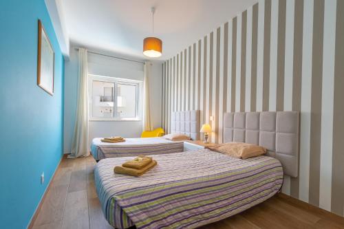 two beds in a room with striped walls at Apartamento Deluxe Oldtown 30 by Umbral in Albufeira