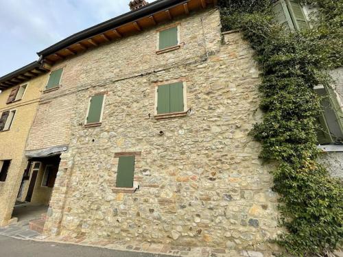 a stone building with green windows on it at Alloggio con camino nel borgo del castello in Albinea