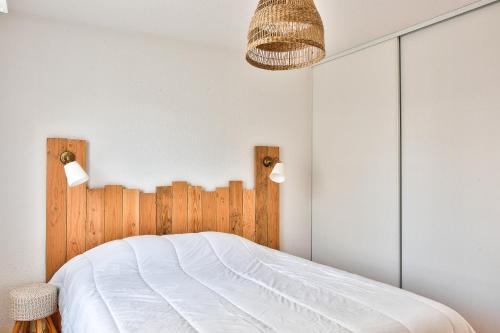 een slaapkamer met een wit bed en een houten hoofdeinde bij Joli appartement avec terrasse a Fouesnant pour deux! in Fouesnant