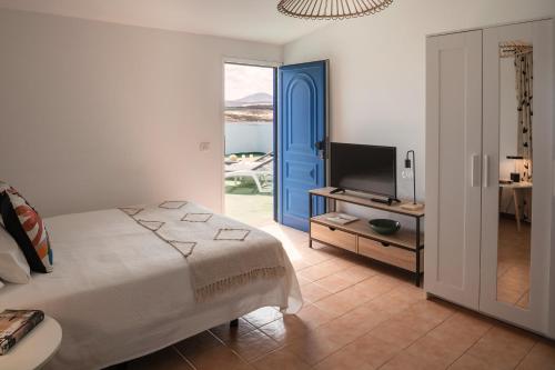 een slaapkamer met een bed en een televisie en een tafel bij Sweet Caleta in Caleta de Caballo