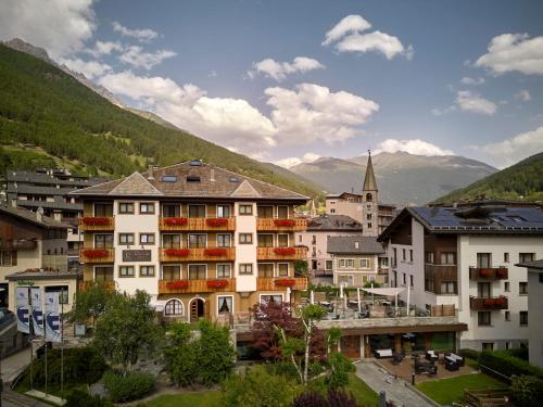 een groep gebouwen in een stad met bergen bij Hotel Rezia in Bormio