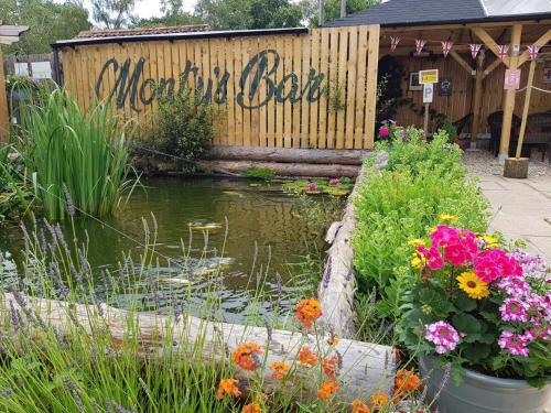 a garden with a pond and a sign that reads monday dealer at Glamping at Back Of Beyond Touring Park in Saint Leonards