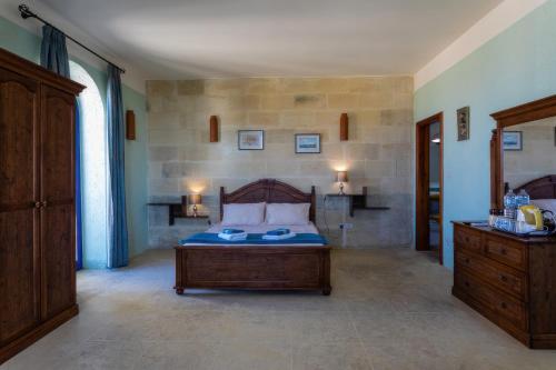 a bedroom with a bed and a wooden dresser at Villa Serenity B&B in Sannat