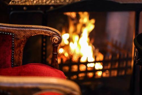 a chair in front of a fireplace with a fire at Fischers Baslow Hall - Chatsworth in Baslow