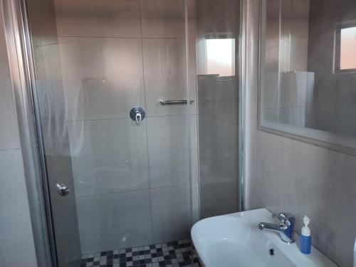 a bathroom with a shower with a sink and a toilet at Coastal Beach Resort in Umkomaas