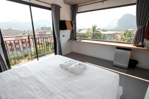 a bedroom with a bed with two towels on it at M&M Hotel in Vang Vieng