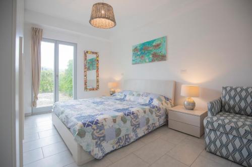 een slaapkamer met een bed, een stoel en een raam bij Appartamento Barbarossa by HelloElba in Porto Azzurro