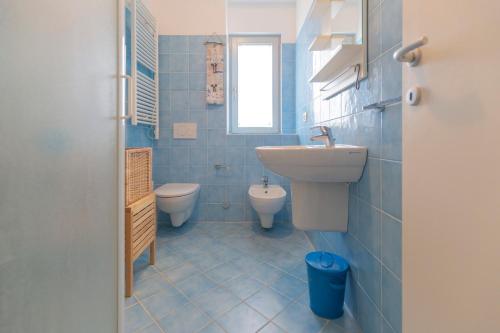 La salle de bains est pourvue de carrelage bleu, d'un lavabo et de toilettes. dans l'établissement Appartamento Barbarossa by HelloElba, à Porto Azzurro
