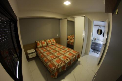 a small bedroom with a bed and a mirror at Ap no coração de POA in Porto Alegre