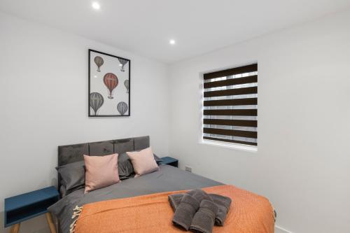 1 dormitorio con 1 cama con manta naranja y ventana en Star London Station Road 2-Bed Retreat with Garden en Londres