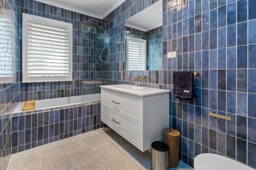 een blauw betegelde badkamer met een wastafel en een bad bij Carinya Arthurs Seat in Arthurs Seat