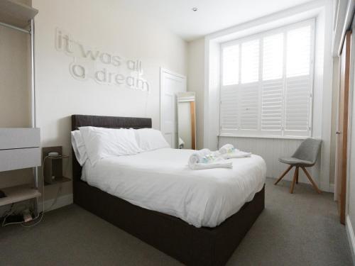 a bedroom with a bed with white sheets and a window at PER7-FM · Nice 1 Bed Ground Floor Flat, near Cessnock Subway in Glasgow