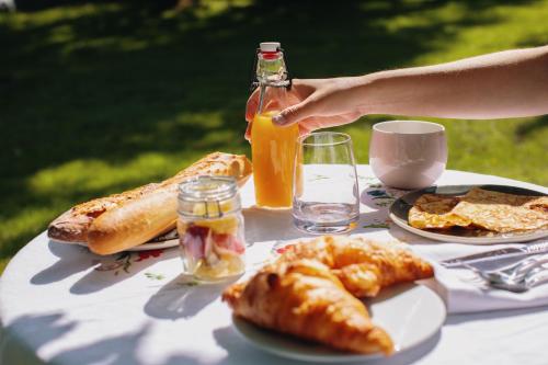 a table with plates of food and a bottle of orange juice at Les gites de Kerégal - la cabane de Charlotte in Plouha