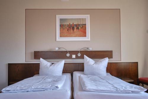 two beds in a hotel room with a picture on the wall at Eisenberger Hof in Moritzburg