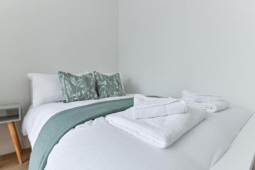 een wit bed met groene en witte handdoeken erop bij Claude House - charming 4Bedroom Home in Nottingham