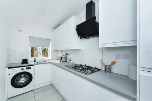een witte keuken met een fornuis en een wasmachine bij Claude House - charming 4Bedroom Home in Nottingham