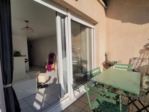 d'un balcon avec une table verte et une porte en verre. dans l'établissement Aix-les-Bains appartement centre ville avec terrasse et box privé, à Aix-les-Bains