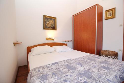 a bedroom with a bed with a wooden headboard at Apartment Smokvina P in Baška