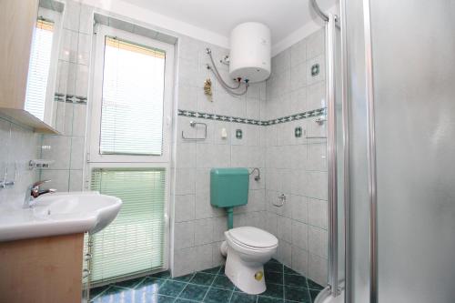 a bathroom with a toilet and a sink and a shower at Apartment Smokvina P in Baška