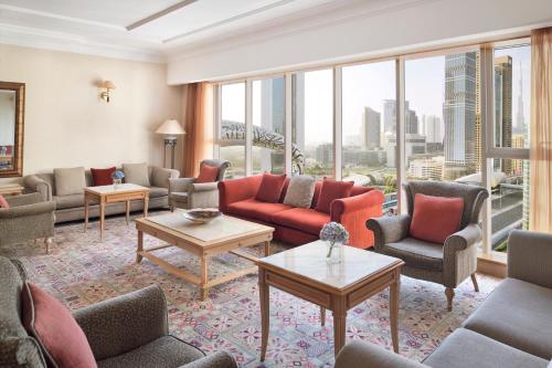 a living room with couches and chairs and windows at Millennium Plaza Downtown, Dubai in Dubai