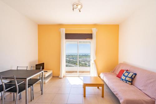 ein Wohnzimmer mit einem Sofa, einem Tisch und einem Fenster in der Unterkunft Vista Albufeira Apartments by Umbral in Albufeira