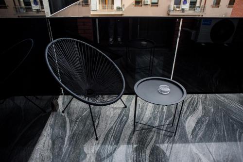a chair and a table with a drink on it at Opera Apartments in Cluj-Napoca