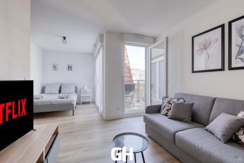 a living room with a couch and a tv at Le Season - Bel appartement - Proche Disney & Paris RER E in Villiers-sur-Marne