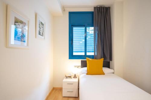 a small bedroom with a yellow pillow on a bed at Lucas House Apartments by Sitges Group in Sitges