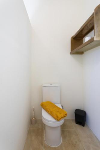 a bathroom with a toilet with a yellow towel on it at Villa Serenity B&B in Sannat