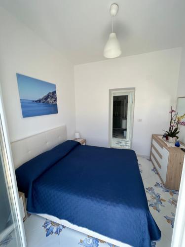 a bedroom with a blue bed in a white room at Casa Piccina in Praiano