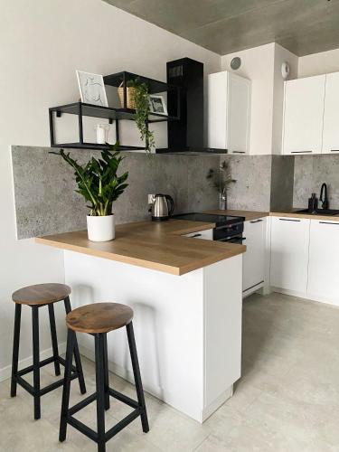 a kitchen with white cabinets and a counter with stools at IgoAparts Wroblewskiego in Łódź