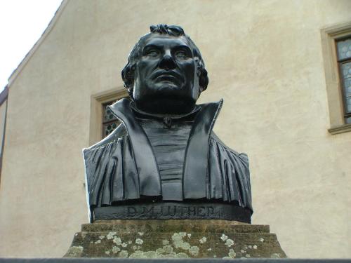 a statue of a man standing in front of a building at Hotel garni Pension Zur Lutherstadt in Lutherstadt Eisleben