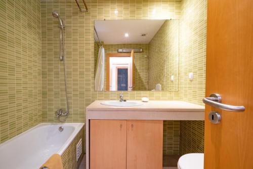 y baño con lavabo, bañera y espejo. en Apartamento Corcovada by Umbral, en Albufeira
