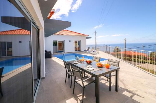 a dining table on the balcony of a house at Villa Calhetascape by Villa Plus in Estreito da Calheta