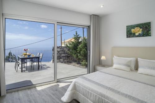 a bedroom with a bed and a table and a balcony at Villa Calhetascape by Villa Plus in Estreito da Calheta