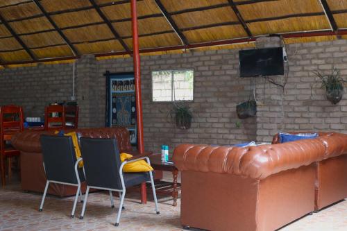 a room with a leather couch and chairs and a television at Mawuya Lodge in Victoria Falls