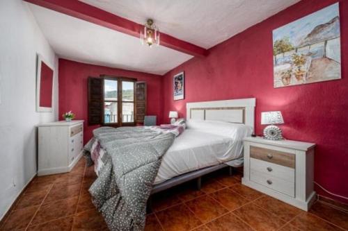 a bedroom with a large bed and a red wall at El-Cason 1 in Almuñécar