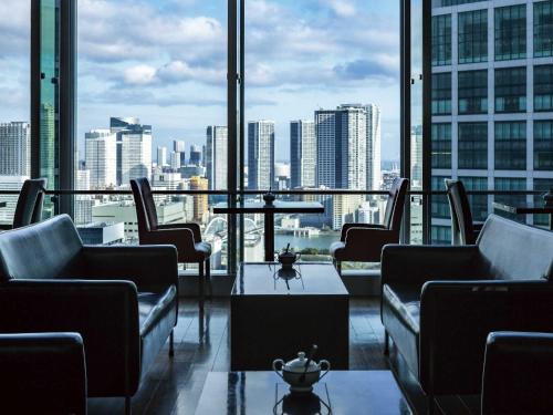 um quarto com cadeiras, uma mesa e uma grande janela em The Royal Park Hotel Iconic Tokyo Shiodome em Tóquio