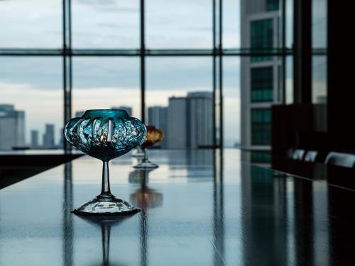 two wine glasses sitting on a table in front of a window at The Royal Park Hotel Iconic Tokyo Shiodome in Tokyo