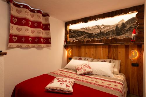 a bedroom with a bed with a window and a red blanket at C'era una Volta in Valtournenche
