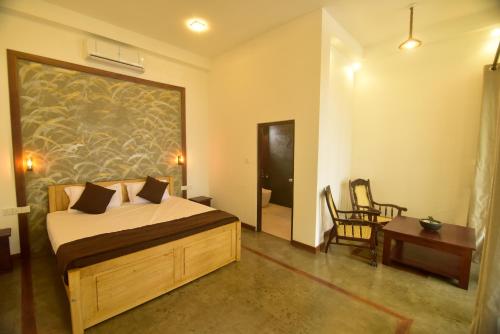 een slaapkamer met een bed, een tafel en een stoel bij Hiru Lagoon Negombo in Negombo