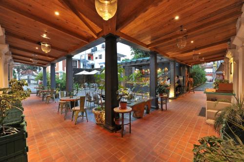 a patio with tables and chairs under a wooden pergola at Seto Ghar Hotel in Kathmandu